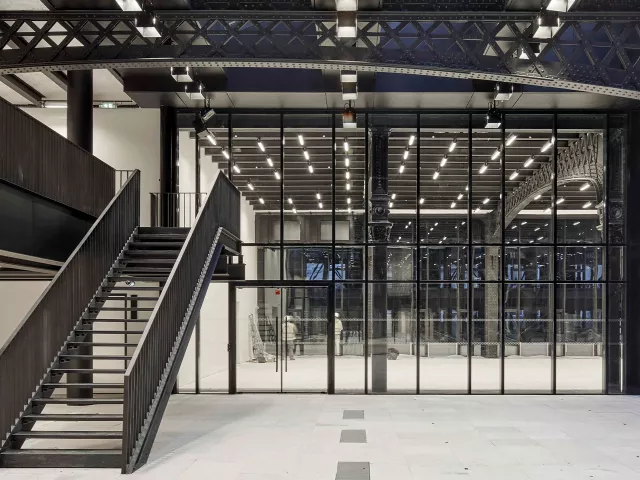 Modern architectural interior with fire rated glass partitions and metal staircase.