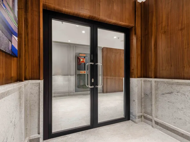 Fire-rated glass door, in a hallway with wood paneling and a light-colored floor.
