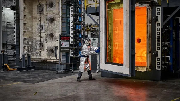 Fire resistance testing in a laboratory with a person in a protective suit standing between two large furnaces