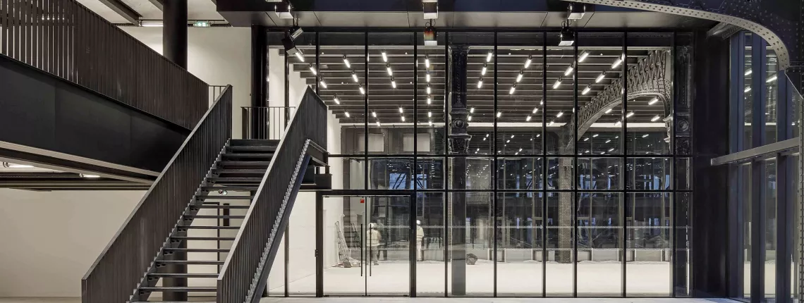 Modern architectural interior with fire rated glass partitions and metal staircase.