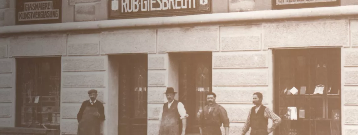 Giesbrecht History 1884 - Junkergasse, Bern Historical Vetrotech image showing a storefront with period signage and men, highlighting its long history.