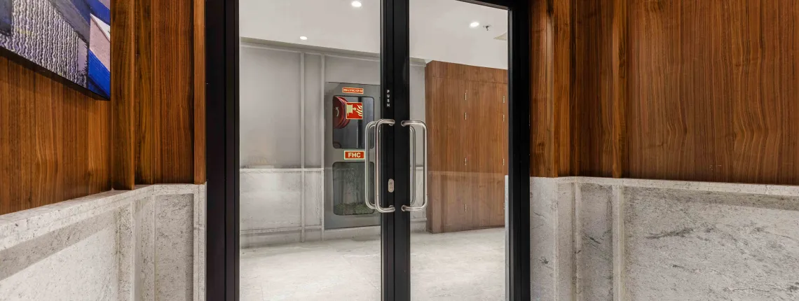 Fire-rated glass door, in a hallway with wood paneling and a light-colored floor.