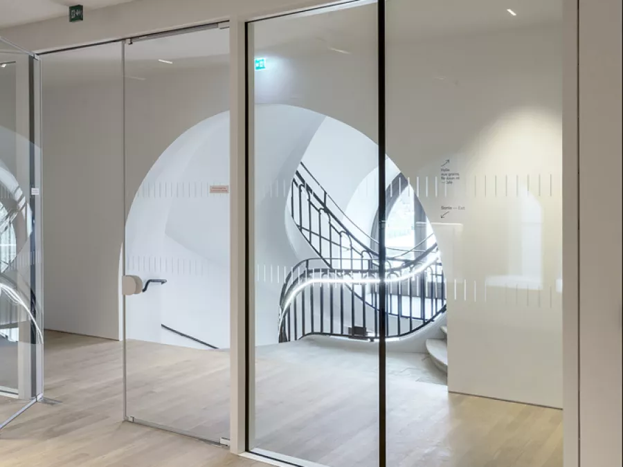 Fire-rated glass doors leading to a room with a spiral staircase, showcasing Vetrotech’s fire protection.