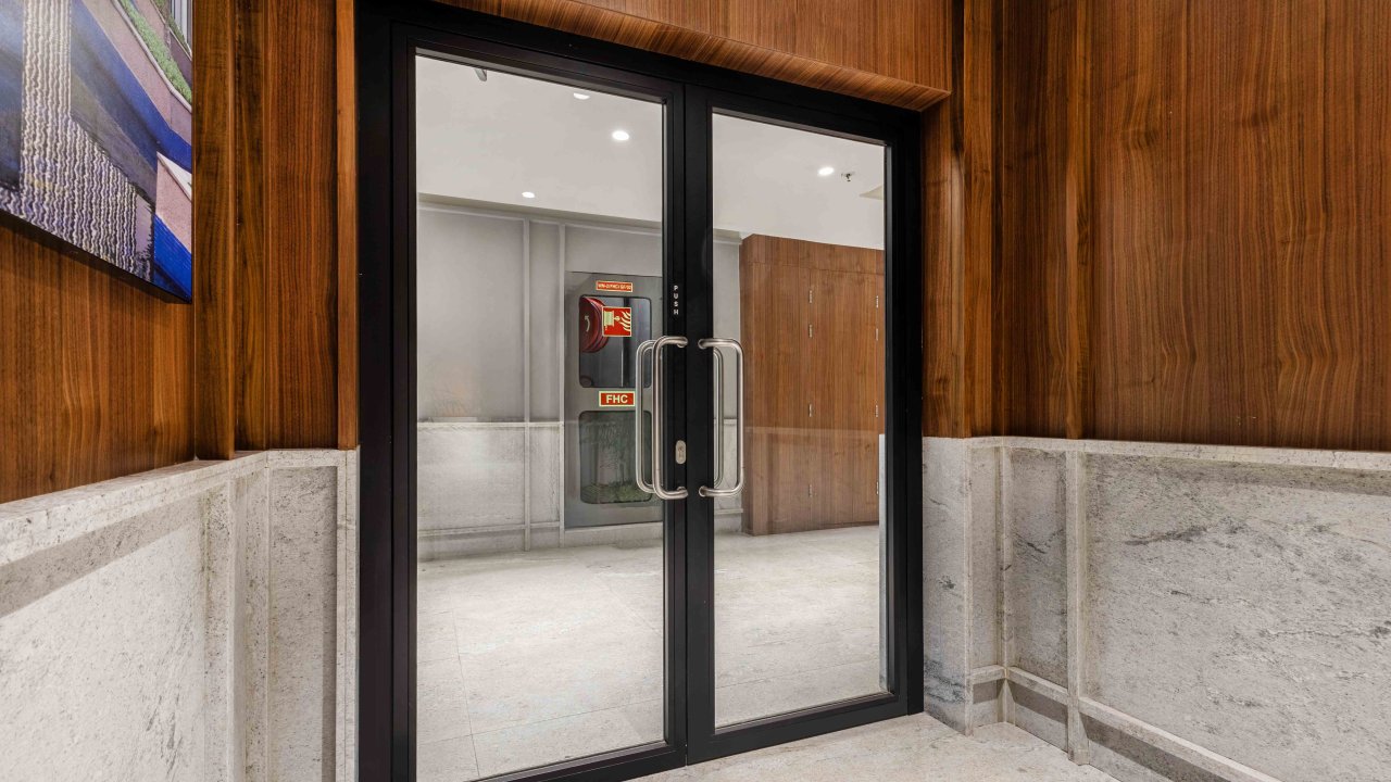 Fire-rated glass door, in a hallway with wood paneling and a light-colored floor.